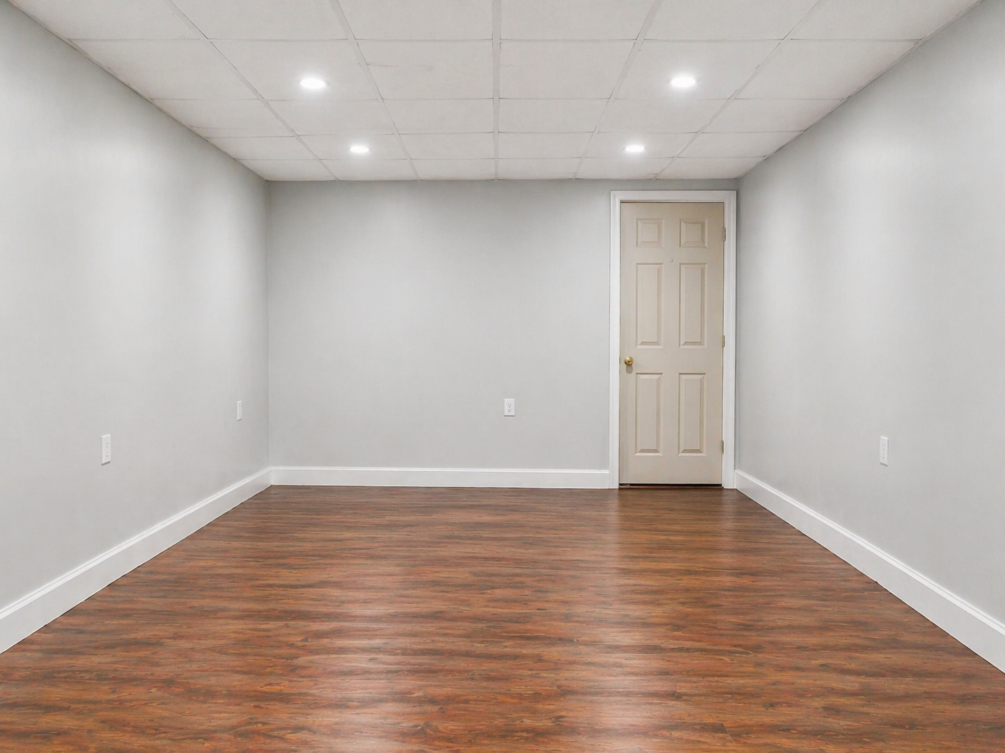 Modern finished basement remodeling project in Detroit, MI with recessed lighting, new flooring, and clean wall finishing